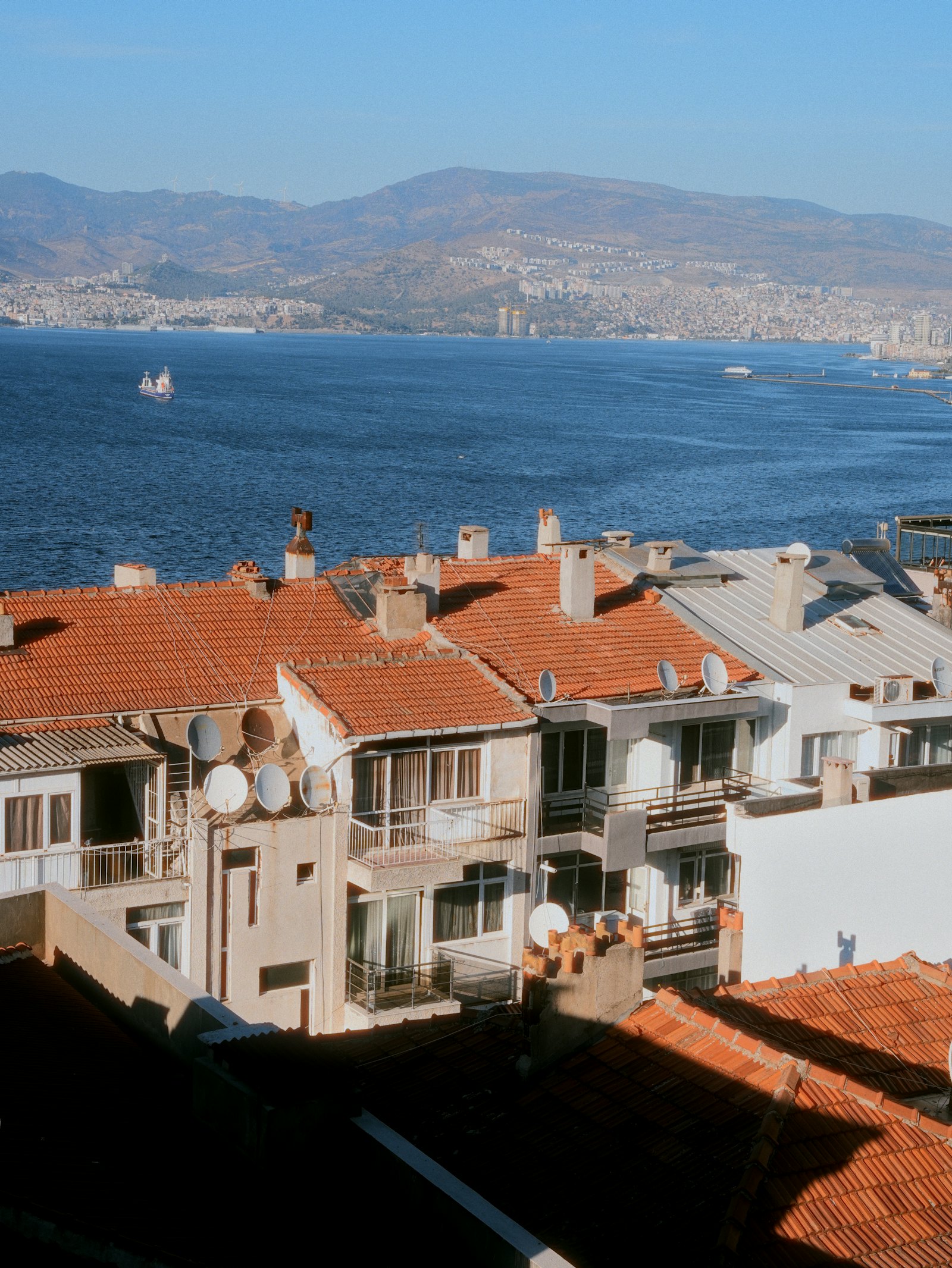 Στέγες παραθαλάσσιας μεσογειακής πόλης πάνω από γαλάζιο κόλπο